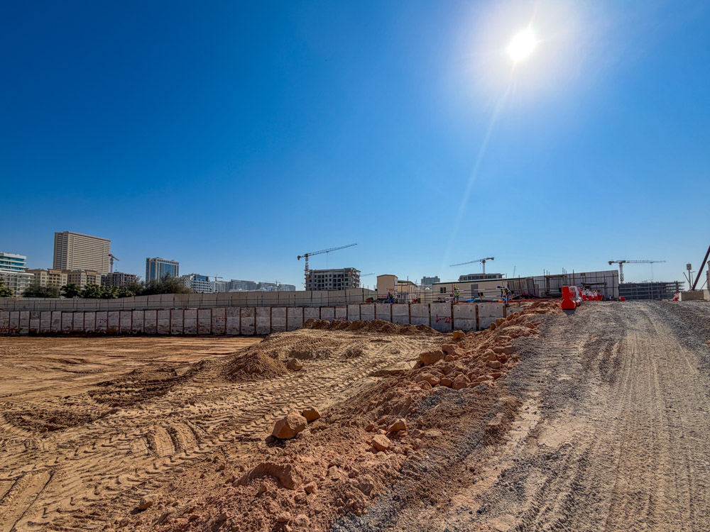 Cove Grand By Imtiaz Construction site with machinery, piles of dirt, and buildings in the background under a clear blue sky.
